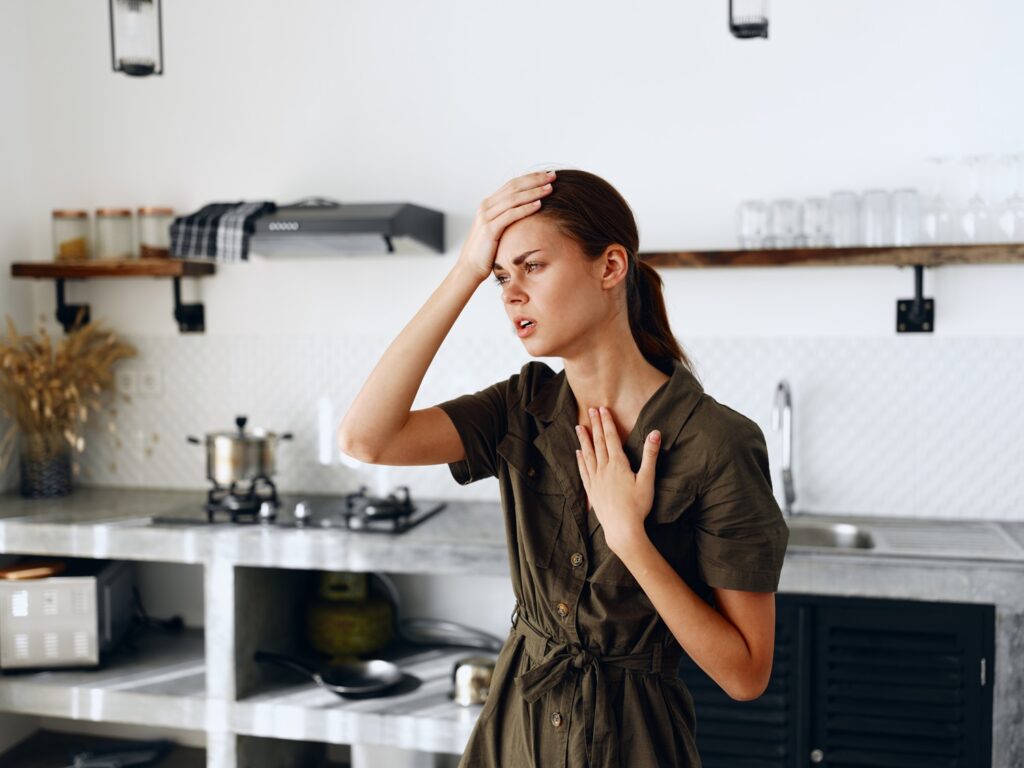 Portrait of a sad tired woman with a sore head in the kitchen, domestic problems, unstable emotional state, tears from onions, cooking dinner in the kitchen at home